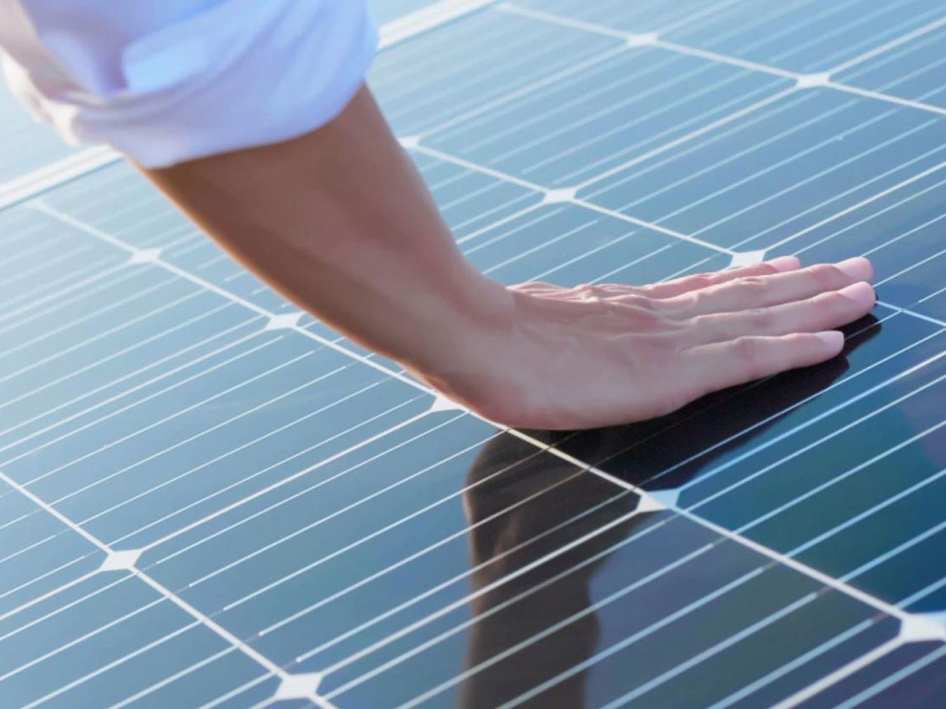 O mână atingând modulele fotovoltaice. 