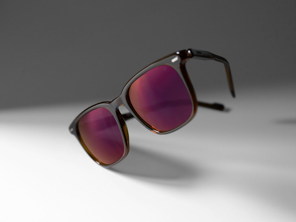 Imaginea unor lentile ZEISS pentru ochelari de soare cu rețetă, cu tratament pentru lentile ZEISS DuraVision Gold UV pe lentile de ochelari de soare vișinii.