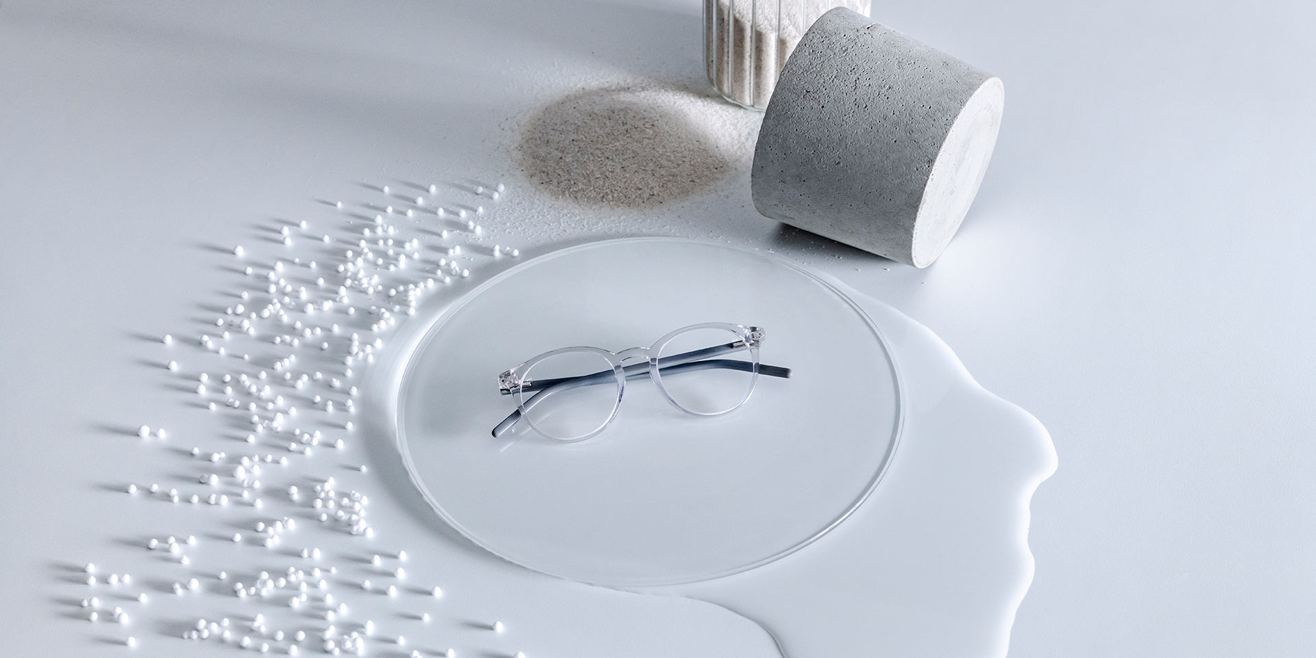 Lentile ZEISS cu tratament DuraVision® așezate pe un piedestal de sticlă înconjurat de apă, nisip, mărgele și piatră.