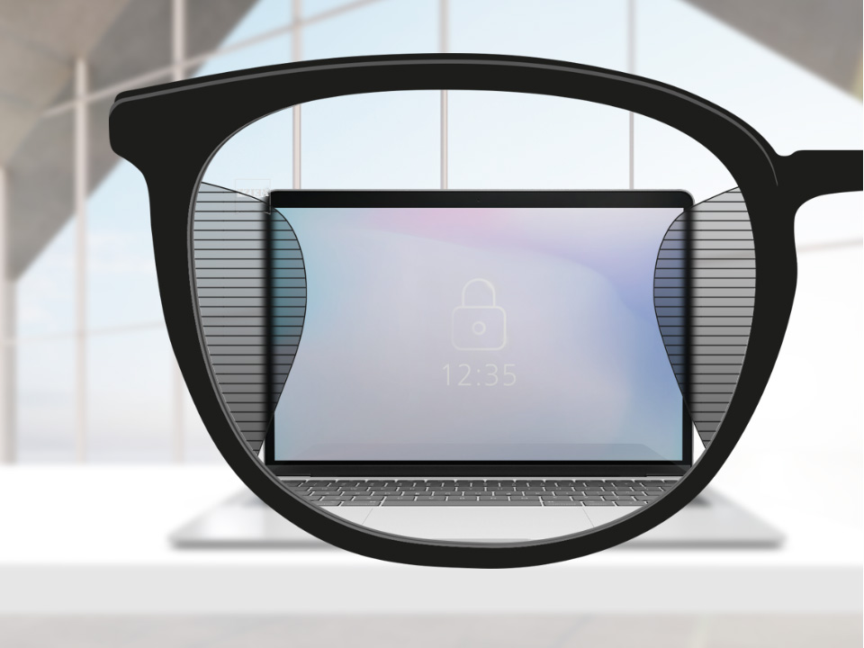 O imagine cu punct de vedere cu lentilele de birou ZEISS Office cu un ecran de calculator în centru lentilelor și cu părți subțiri neclare la stânga și la dreapta.