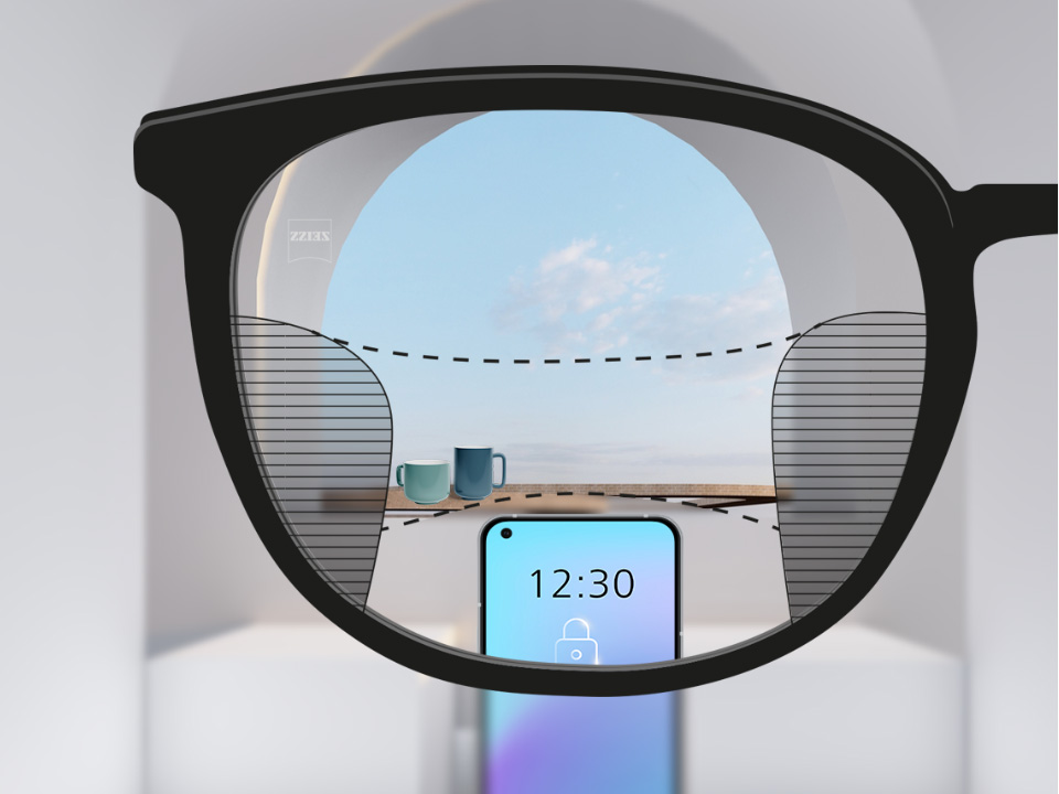 O imagine cu punct de vedere cu lentilele progresive ZEISS SmartLife cu un smartphone și cești pe fundal, iar lentilele sunt complet incolore, cu părți subțiri neclare la stânga și la dreapta.