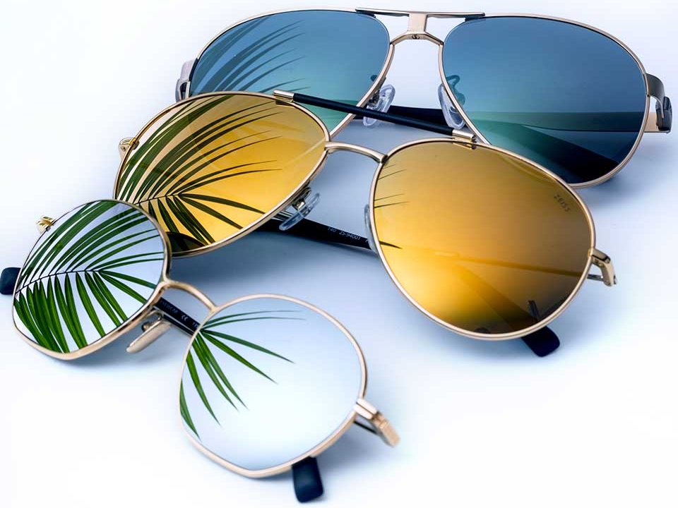 Fotografie cu trei ochelari de soare cu tratamente pentru lentile tip oglindă în diferite culori (incolor, galben și albastru) 