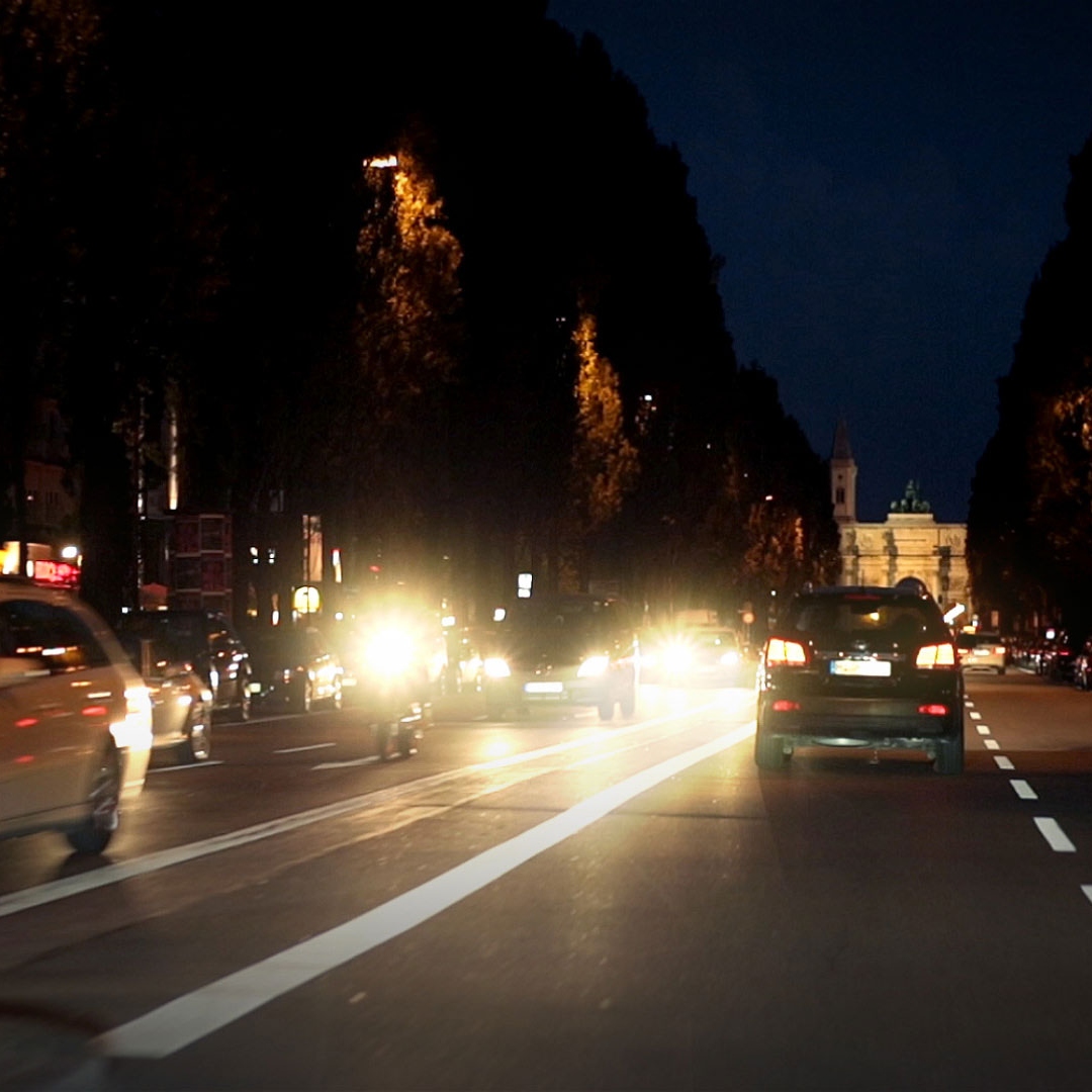 Reflexii orbitoare de la mașinile care circulă în sens opus noaptea și reflecție de la drumurile umede 