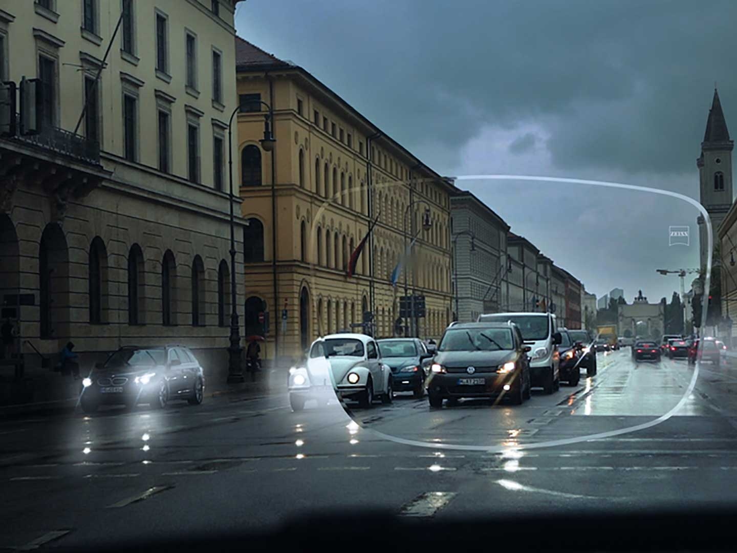 Imaginea prezintă vizibilitate scăzută în condiții de lumină redusă pe o stradă. Punctul de vedere este interiorul unei mașini, așa cum se vede prin lentilele de ochelari. 