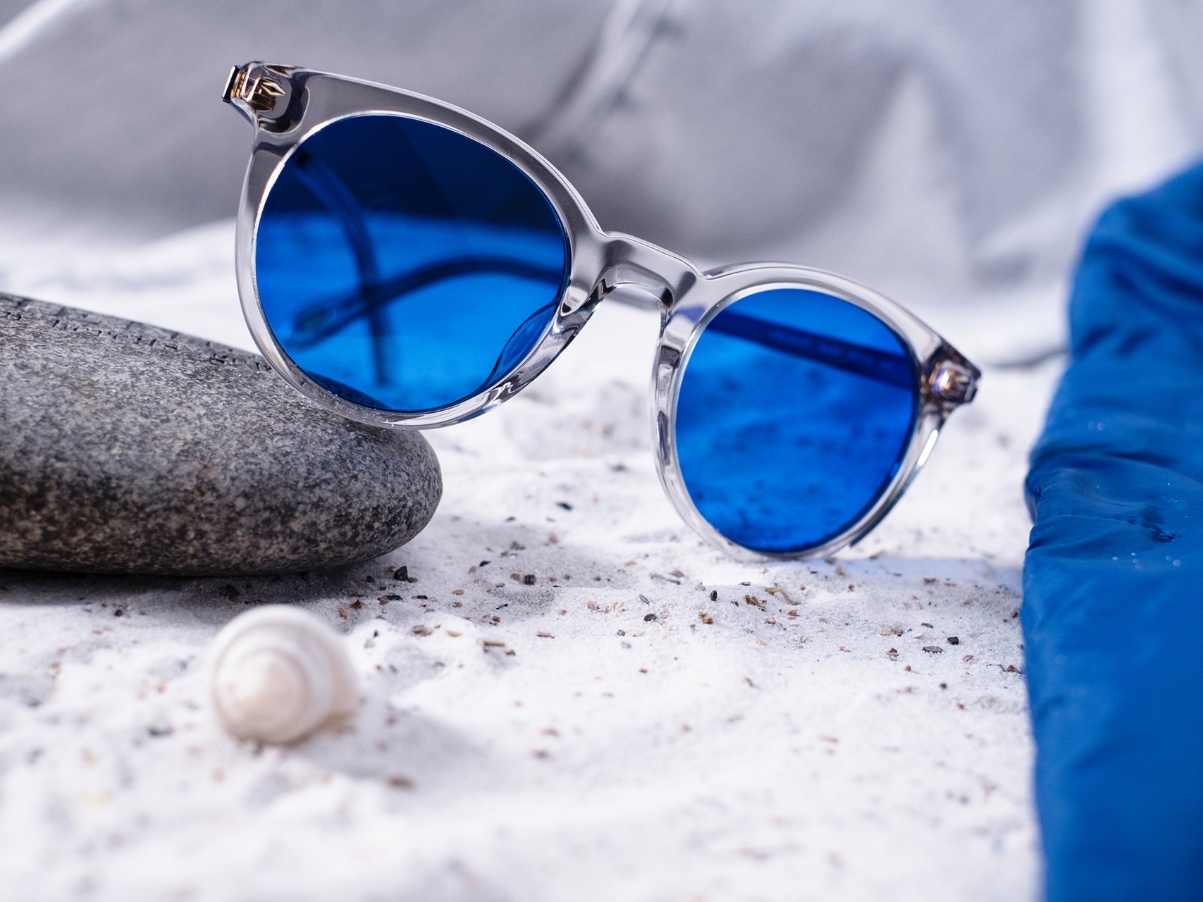 Imagine a unei perechi de ochelari de soare cu nuanță albastră pusă pe jumătate pe o piatră