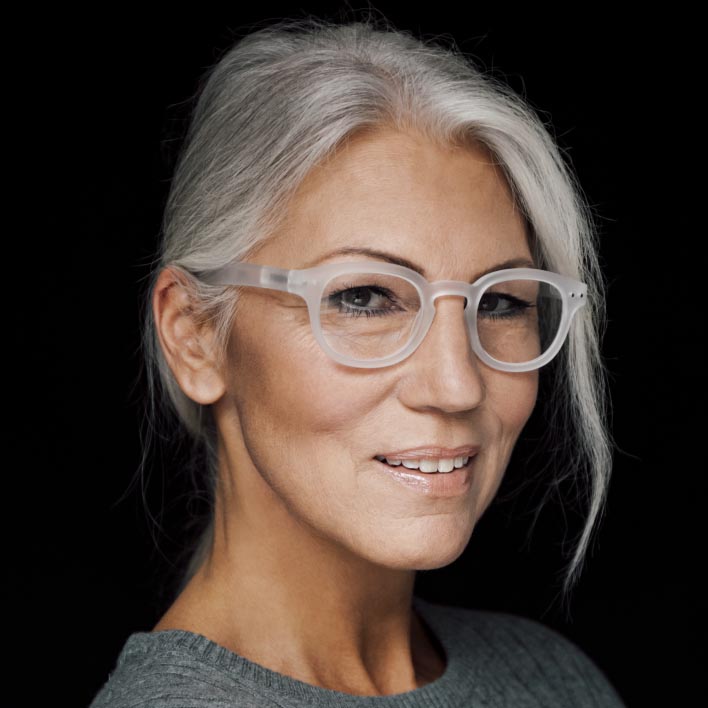 Femeie cu părul gri, cu ramă albă, cu lentile progresive ZEISS SmartLife. Scanare geometrică a feței care prezintă anatomia facială și măsurătorile ramelor.